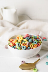 Bowl with tasty cereal rings and spoon on light wooden background