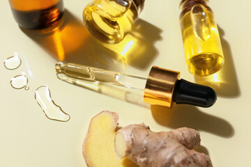 Bottles with ginger essential oil on color background