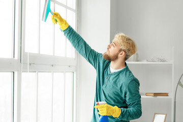 Young man cleaning window at home