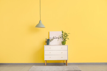 Stylish lamp and chest of drawers near color wall in room