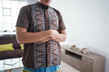 portrait of asian muslim praying by fold arm in front of a chest at home