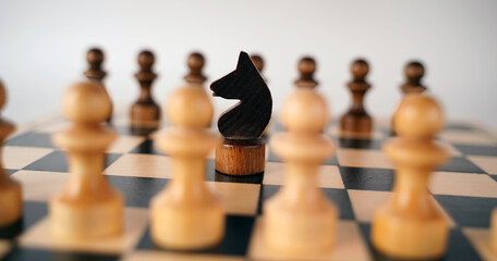 White and black wooden pieces on a chessboard. A chessboard set up during a game on a gray...