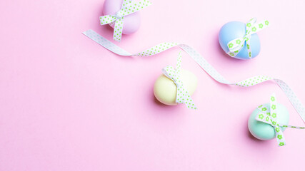 Easter luxury. Colorful egg with tape ribbon on pastel pink background in Happy Easter decoration. Flat lay, top view.