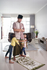 muslim father being disturbed by his daugther while praying at home