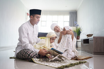 portrait of happy muslim family with children reading quran and pray together at home © Odua Images