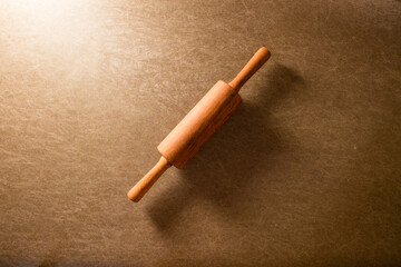 wood rolling pin put on brown texture background with lighting