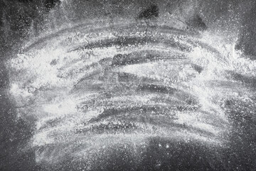 Fresh wheat floor spilled on black background, top view