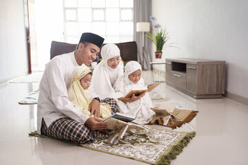 portrait of happy muslim family with children reading quran and pray together at home © Odua Images