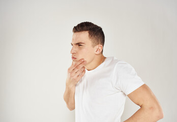 A guy in a white T-shirt gestures with his hands on a light background emotions model cropped view