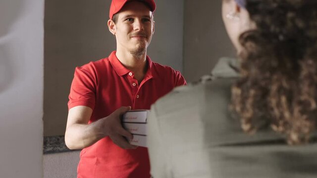 home delivery - young courier delivers pizzas to a young woman at home