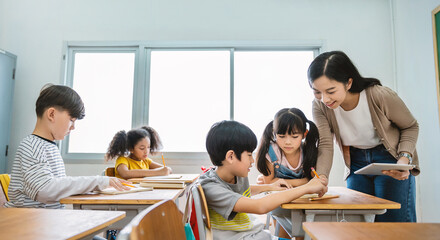 Pupil boy hi five with teacher in classroom at elementary school. Student boy studying in primary...