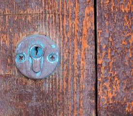 The lock on the old wooden door. The background is a brown aged texture. Closed village house. Free space for text. Front view. A copy of the space. Selective focus.