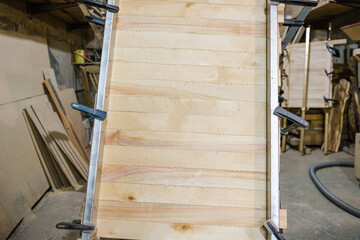 Glue boards. Shield made of boards. Fasten wooden boards together. Carpentry work. Hold with clamps. The glue flows.