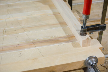 Glue boards. Shield made of boards. Fasten wooden boards together. Carpentry work. Hold with clamps. The glue flows.