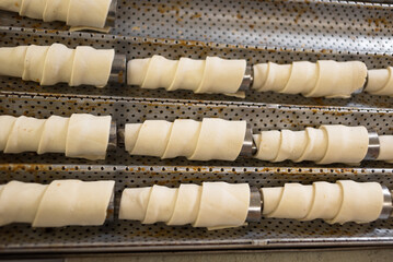 Rolls of raw puff pastry on a metal cone. Baking in a pastry shop.