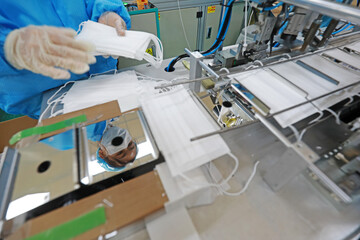 Workers are busy on the production line in a Medical mask factory.