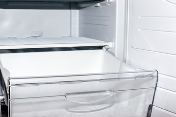 Open plastic white container drawer in refrigerator. Selective focus.