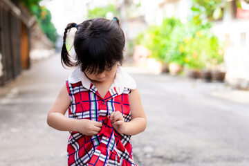 A 3-4 years old girl tries to button her clothes by herself. Self-help. Learning and practicing personal development. Help care to dress button up children concept. Selective focus.