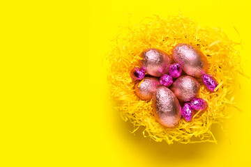 Nest with sweet chocolate eggs on color background