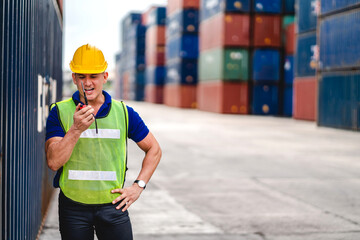 Professional engineer container cargo foreman in helmets working standing and using walkie talkie...