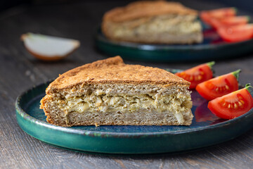 Slice of homemade onion quiche a baked cream and egg pie topped with cheese and green herbs