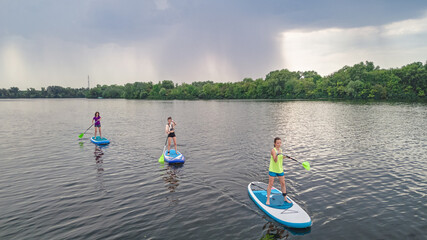 Active family on SUPs, standing up paddleboards, in river water, summer family sport, aerial top...