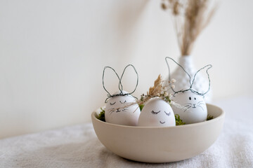 3 Eier als Deko zu Ostern, 2 als Hasen eins als Mädchen mit Blumenkranz in einer Schale. Happy Easter. 