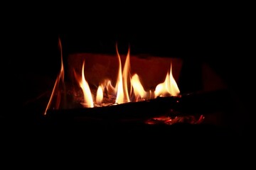Naklejka premium a side view of yellow reddish flame coming out from firewood during night time.