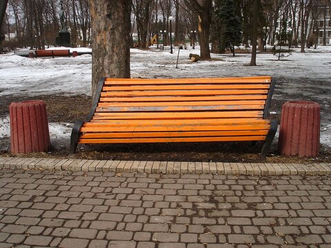 A lopsided park bench painted orange