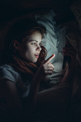 woman holding phone in her hands lying in bed at night lifestyle