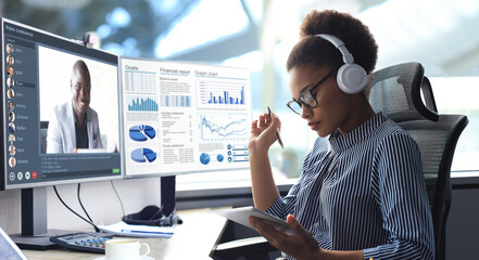 African american entrepreneur using in headphones talking to her colleagues in video conference. Multiethnic business team working from office using PC, discussing financial report of their company.