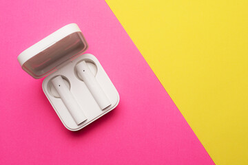 Wireless headphones on a pink background . Bright background. White headphones. Bluetooth headset. Pink and yellow background. Copy space. Modern technologies.