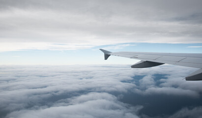 Fototapeta na wymiar Plane wing in a flight and dramatic cloudscape white clouds over europe