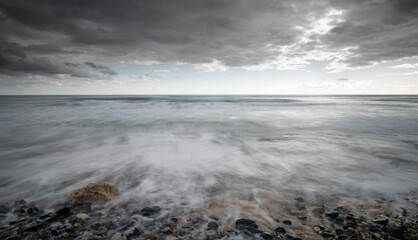 Seawaves splashing to the coast with stones against stormy dramatic cloudy sky. Wintertime, Limassol cyprus