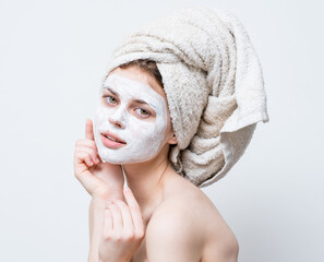 woman with cream on her face towel on her head skin care