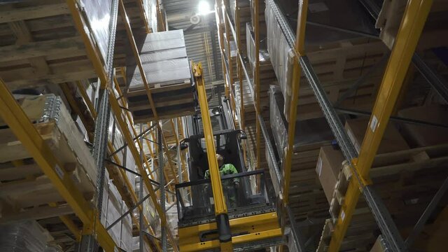 large logistics commerce structure with boxes on the shelf. industry, lifting concept. warehouse worker using car and forklift, loading cardboard goods on racks for transnational export