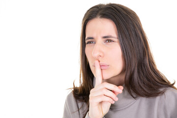Cute mysterious girl showing silence shh sign holding forefinger on lips having secret isolated on...