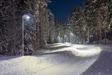 Snow-covered and plowed walkway illuminated with street light in Pitea