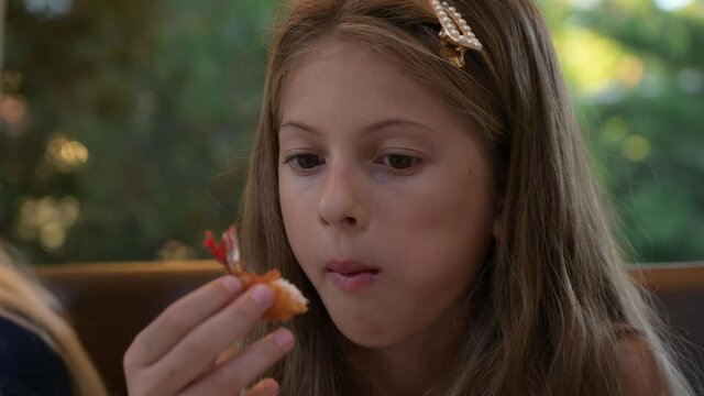 beautiful little caucasian girl eating shrimp food in outdoor cafe during summer leisure activity