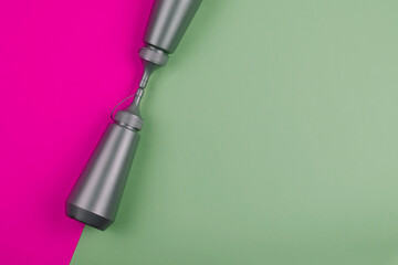 Two gray plastic bottles on a pink and green background.