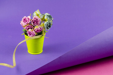 Yellow metal bucket with a bouquet on a two-color abstract geometric background.