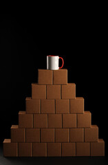 a pyramid of cardboard boxes with a white mug with a red heart on top