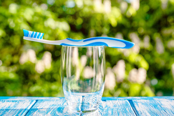 Naklejka na ściany i meble Toothbrush stands in a glass on a natural background 