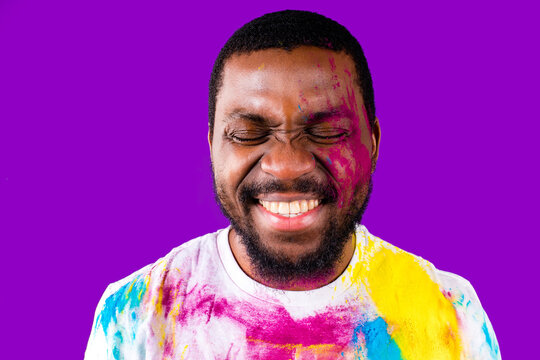 latin brazilian male in white cotton t-shirt with colorful paint of face laughing studio