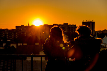 A couple is watching the sunset over the city from the observation deck in Warsaw, Poland (Lens Flair)