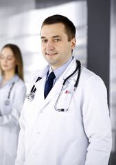 Fototapeta premium Professional middle aged doctor with a stethoscope at work with colleagues in a clinic. Perfect medical service in a hospital. Medicine and healthcare concept