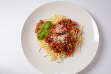 Traditional Italian spaghetti Bolognese  served on a white plate with tomatoes and basil