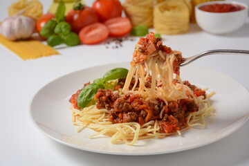 Traditional Italian spaghetti Bolognese  served on a white plate with tomatoes and basil