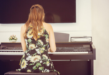 Rear view of Beautiful woman in dress playing piano, Young girl playing grand piano at home