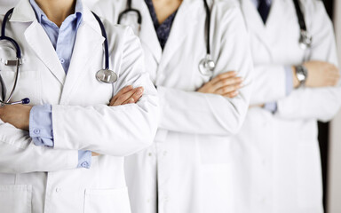 Group of modern doctors standing as a team with arms crossed in hospital office and ready to help patients. Medical help, insurance in health care, best disease treatment and medicine concept